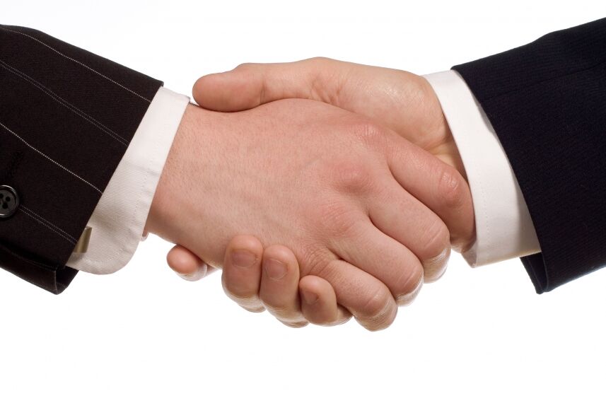 A close-up handshake between two suited people — partnership motif.