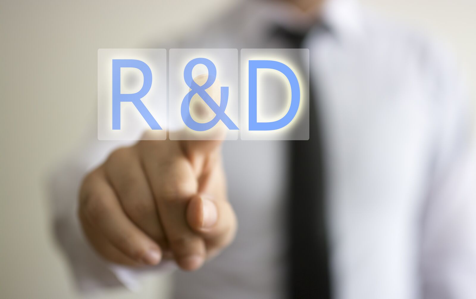 A businessman pointing at an R&D label on a translucent screen — research-and-development motif.